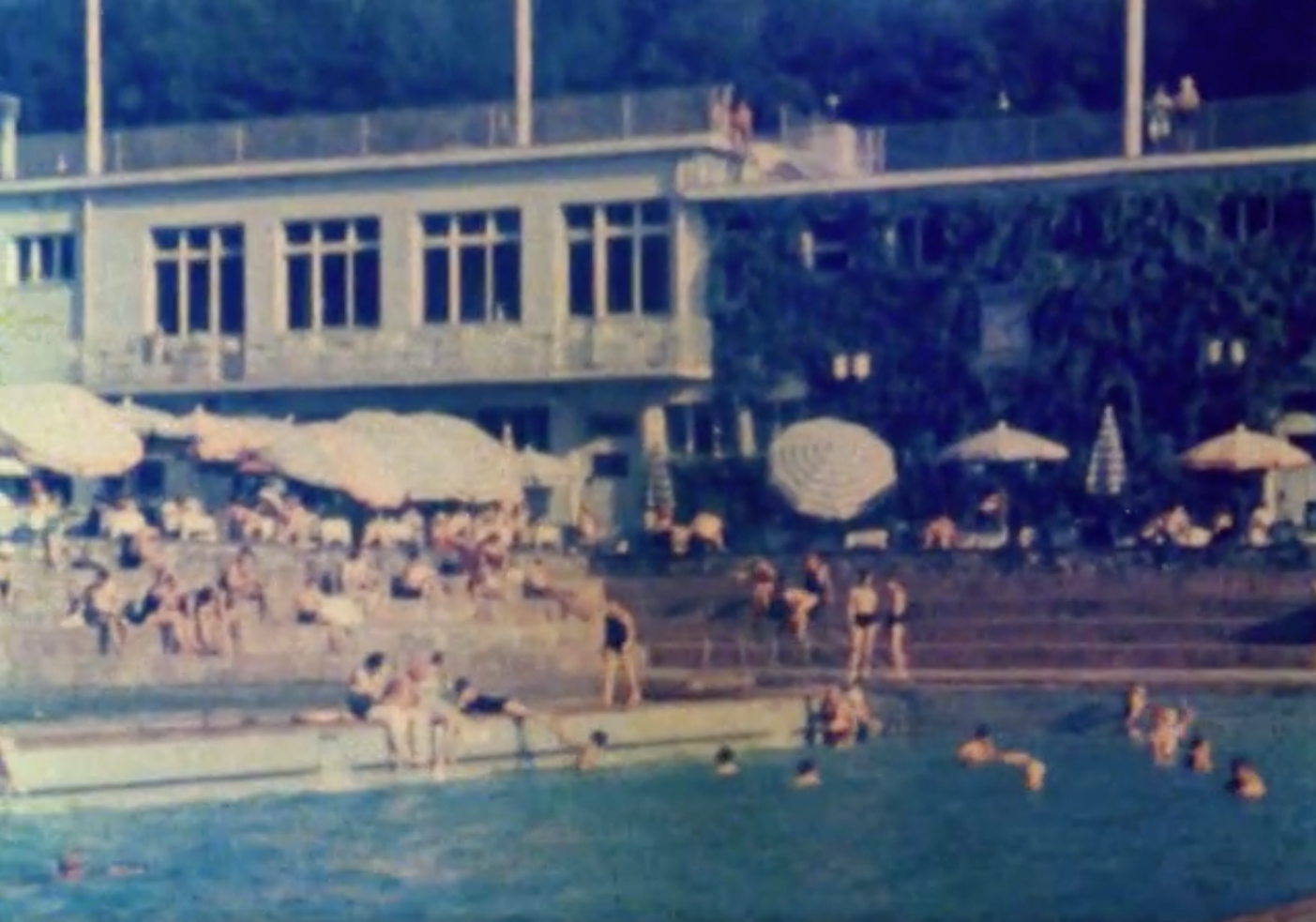 The film starts with a sheaf of paperwork being studied prior to the conference with the intertitle 'The Temptation to Go' and follows the decision to attend with the journey to Switzerland by plane. It turns out that the 'auditorium' is the hotel swimming pool packed with swimmers. The conference attendees (who are never seen actually at the conference) are seen relaxing and socialising. They have an excursion to Rapperswill; a group of researchers are described as 'Happy Hampstead', there is a sequence with Thomas Mann, other groups of unidentified conference attendees and then souvenirs which are beer mats.